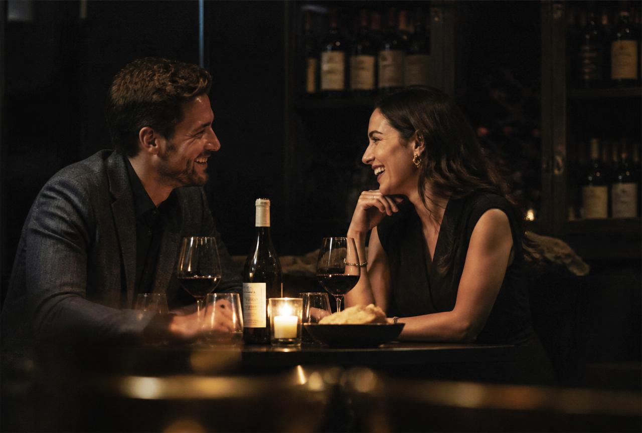 A man and a woman talking and laughing across a candlelit table